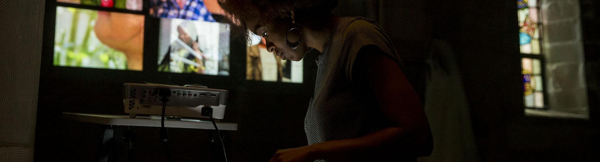 Woman looking at a screen with projected images behind her on a wall.